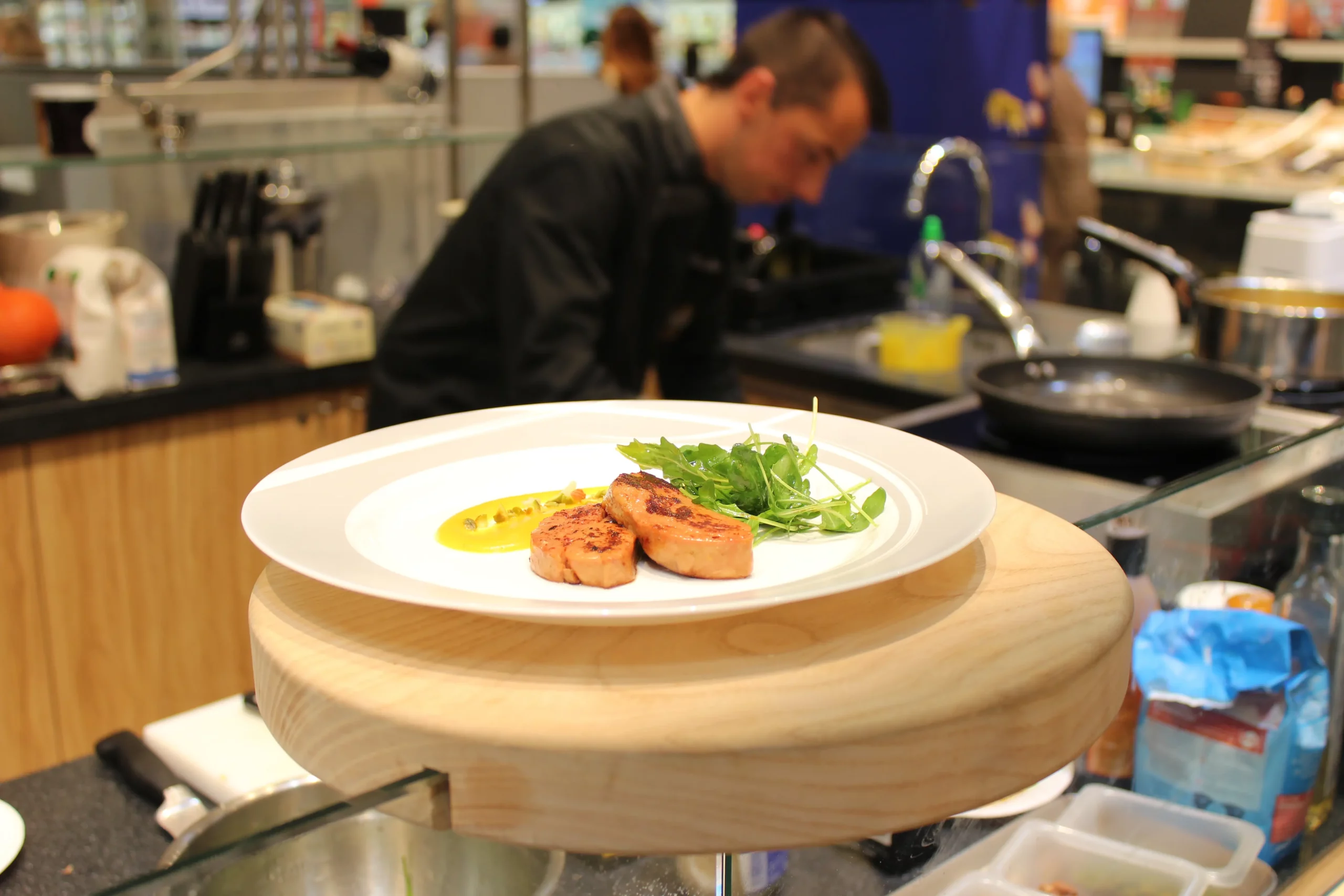 Foie gras poêlé dressé dans une assiette blanche avec salade et purée, en cuisine