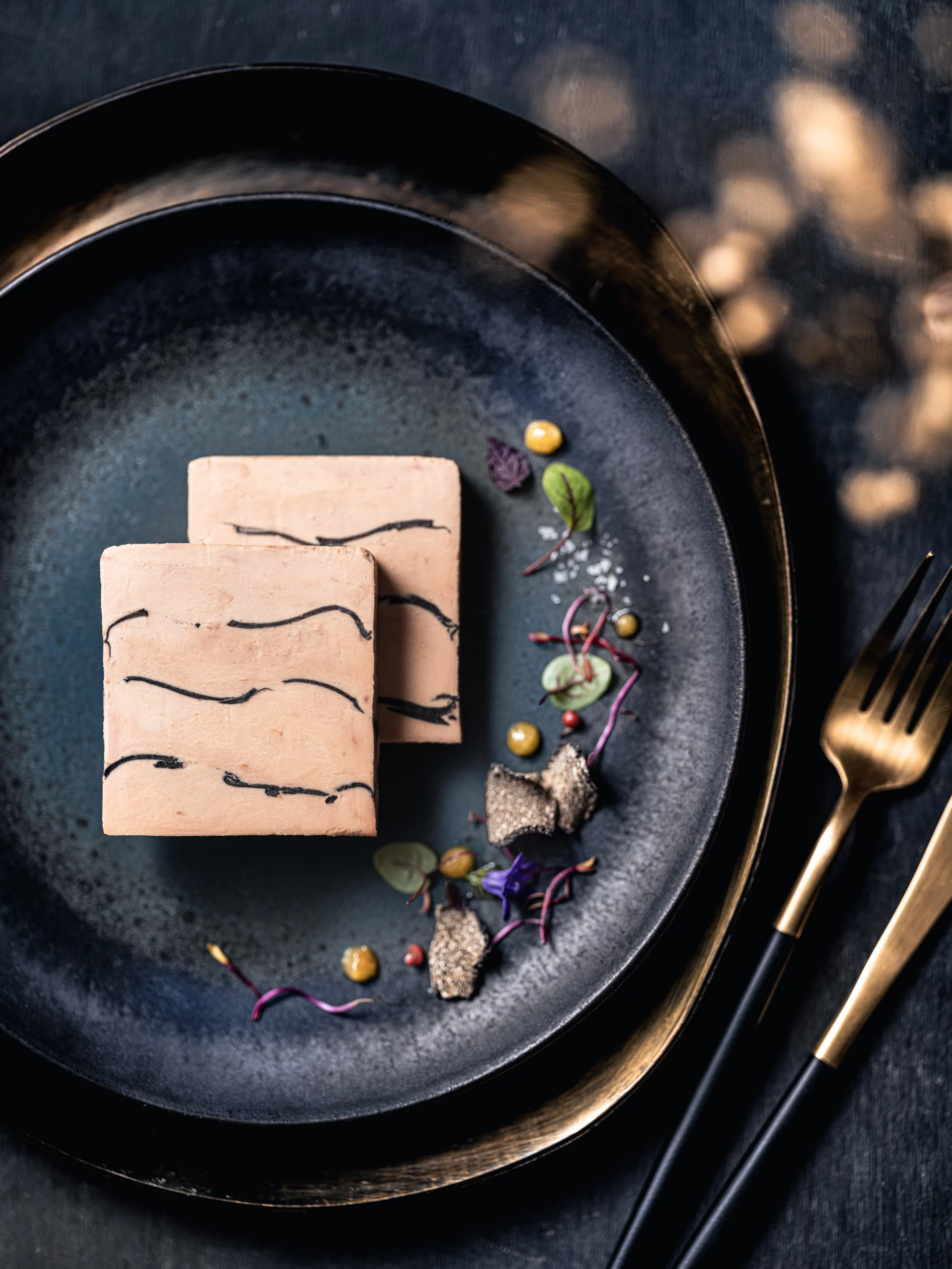 Deux tranches de foie gras marbré à la truffe, accompagnées de condiments et truffes râpées